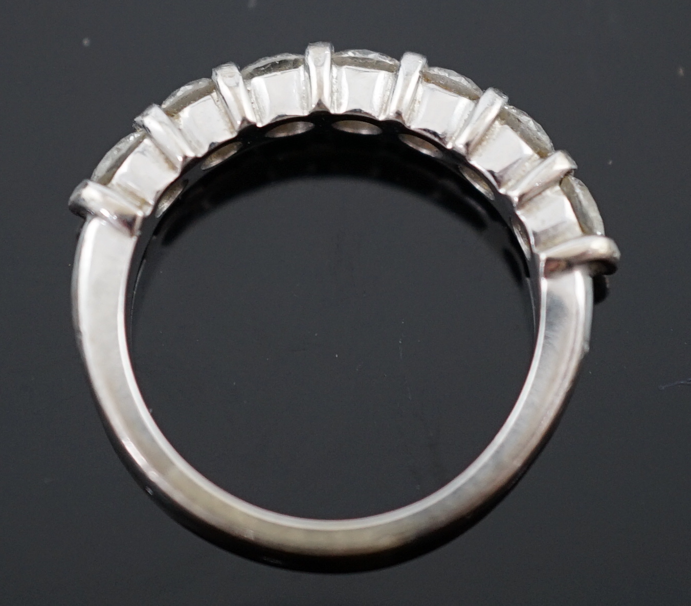 A modern 18ct white gold and seven stone round brilliant cut diamond set half hoop ring